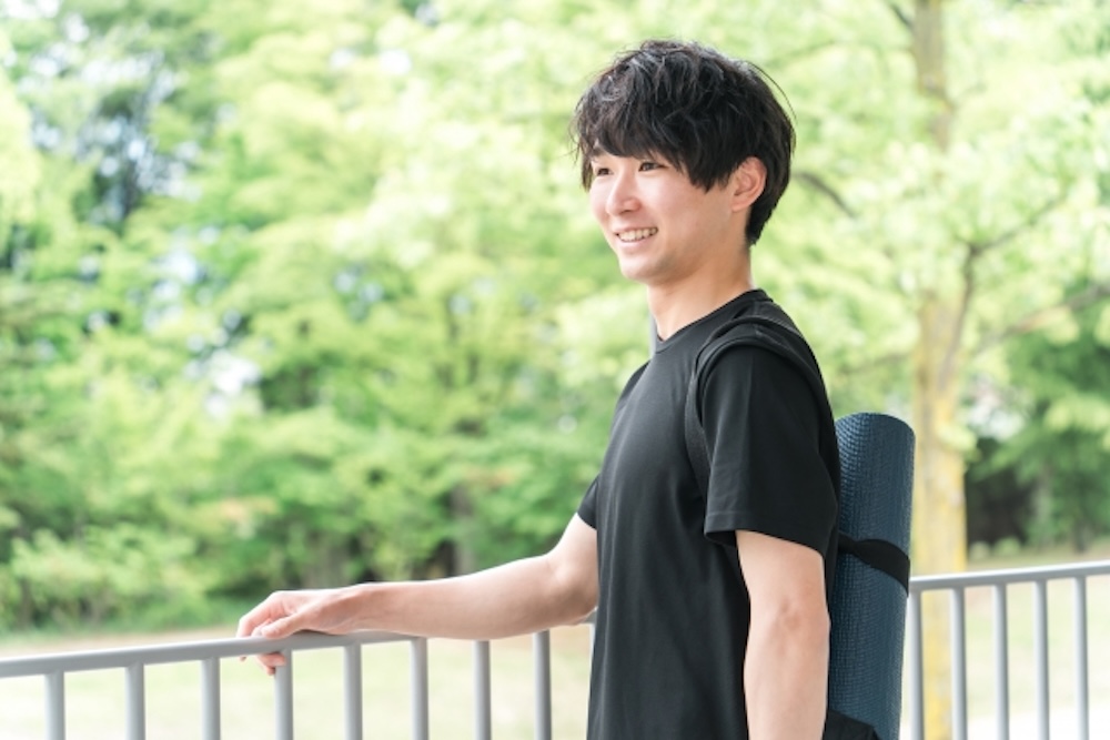 ヨガマットを背負いフィットネスジムに向かう男性